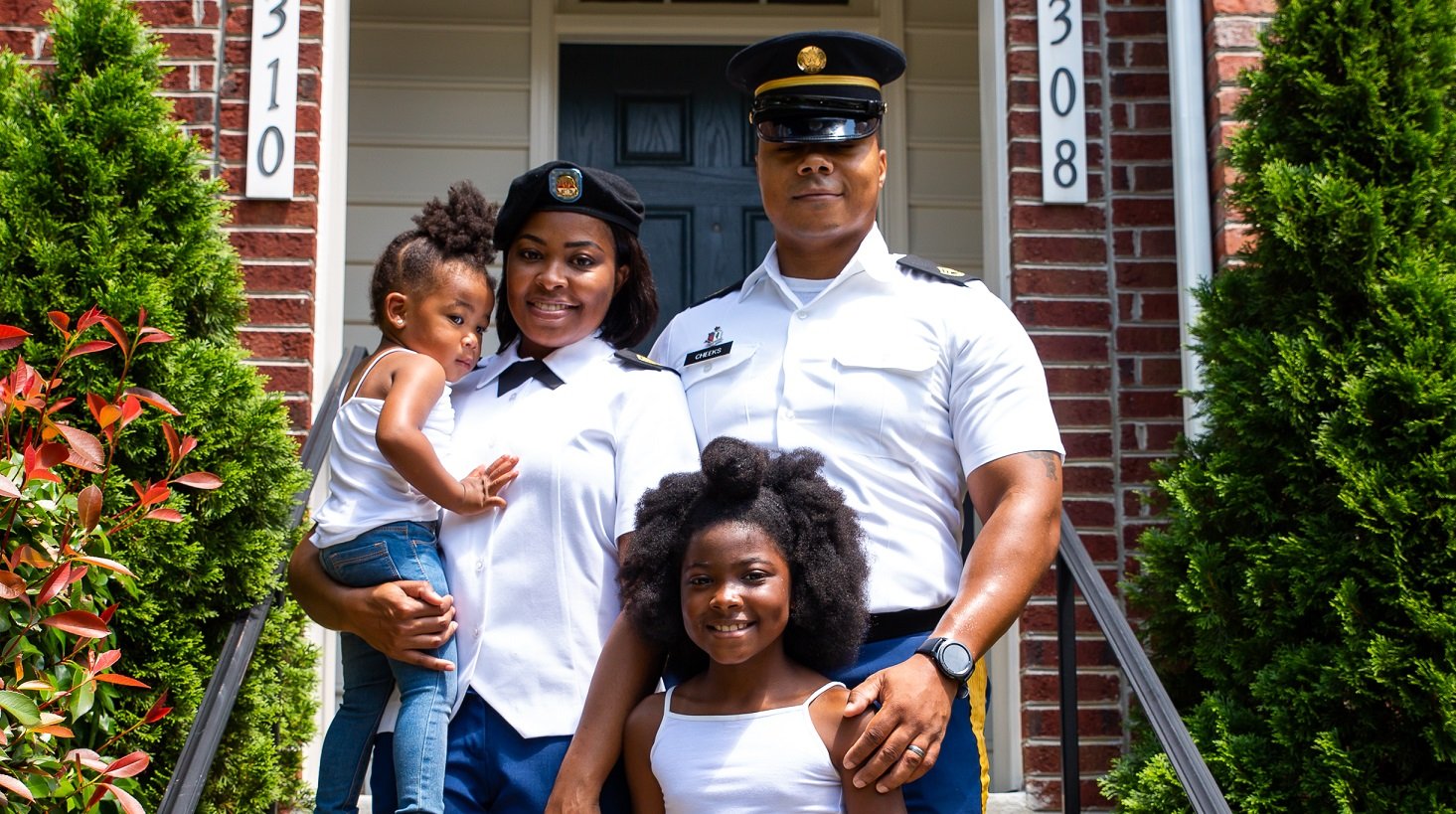 Military family standing in front of their home